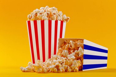 Glass with popcorn on a yellow background close-up