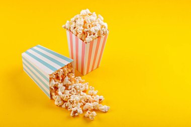 Glass with popcorn on a yellow background close-up