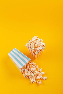 Glass with popcorn on a yellow background close-up
