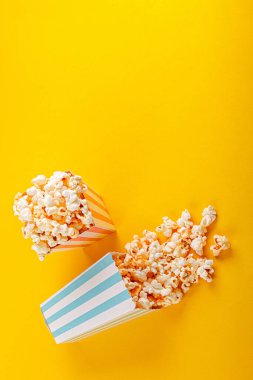 Glass with popcorn on a yellow background close-up