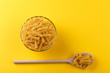 Sarı arka planda farklı şekillerde kuru İtalyan makarnası.