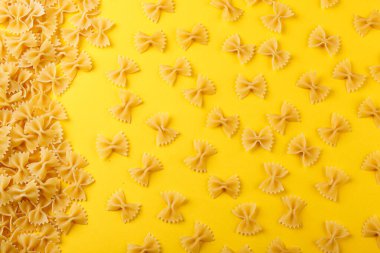 Sarı arka planda farklı şekillerde kuru İtalyan makarnası.