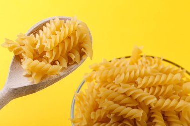 Sarı arka planda farklı şekillerde kuru İtalyan makarnası.