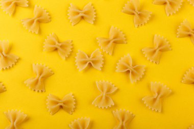 Sarı arka planda farklı şekillerde kuru İtalyan makarnası.