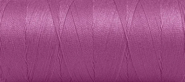 白い背景に紫色のスプール内の糸の質感をクローズアップ — ストック写真