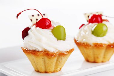 Beyaz arka planda vişneli ve üzümlü güzel kremalı pastalar.