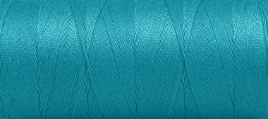 Texture of threads in a spool of turquoise color on a white background close-up