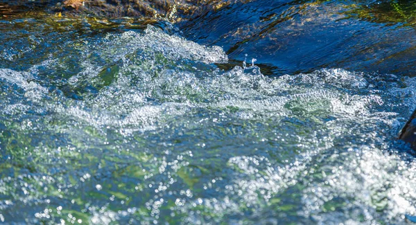石の近くからの水とスプレーの流れ — ストック写真