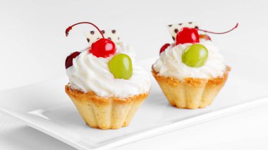 Beyaz arka planda vişneli ve üzümlü güzel kremalı pastalar.