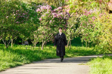 Güzel bir kız yağmurlukla, beyaz gömlekle, siyah pantolonuyla, yakın plan pantolon giyer.