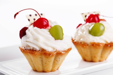 Beyaz arka planda vişneli ve üzümlü güzel kremalı pastalar.