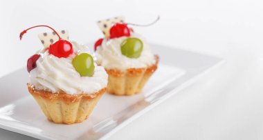 Beyaz arka planda vişneli ve üzümlü güzel kremalı pastalar.