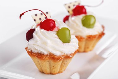 Beyaz arka planda vişneli ve üzümlü güzel kremalı pastalar.