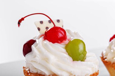 Beyaz arka planda vişneli ve üzümlü güzel kremalı pastalar.