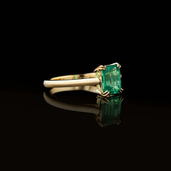 beautiful yellow gold ring with emerald on a black background close-up
