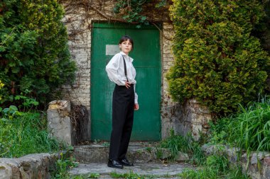 Beyaz gömlekli, siyah pantolonlu, askılı güzel bir kız.