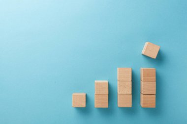 Mavi arka planda eli olan merdiven şeklinde ahşap küpler.