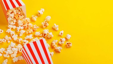 Sarı arka planda patlamış mısırlı karton kutu.