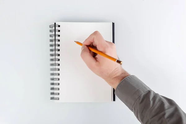 business notepad, hand holding a pencil on a white background close-up