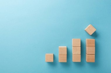 Mavi arka planda eli olan merdiven şeklinde ahşap küpler.