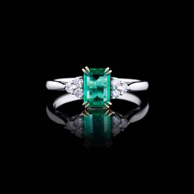 Elmas ve zümrüt kaplamalı güzel beyaz altın bir yüzük.