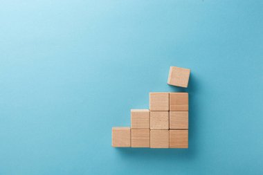 Mavi arka planda eli olan merdiven şeklinde ahşap küpler.