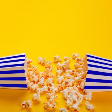 Sarı arka planda patlamış mısırlı karton kutu.