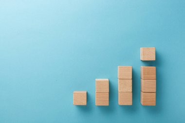 Mavi arka planda eli olan merdiven şeklinde ahşap küpler.