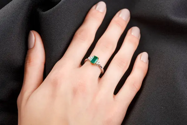 Mooie Vrouwelijke Hand Met Gouden Ring Met Diamanten Smaragd Grijze Stockafbeelding