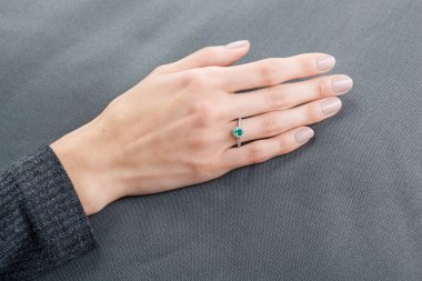Altın yüzüklü, elmaslı ve zümrüt kaplamalı güzel bir kadın eli.