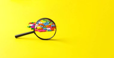 Alfabenin sarı arkaplanda büyüteçle kaplanmış renkli harfleri.