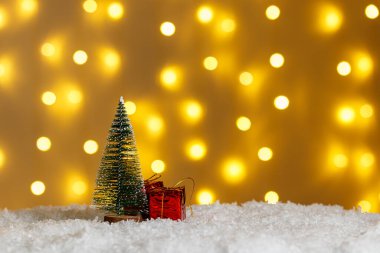 Karda Noel ağacı ve parlak ışıklarda hediyeler.