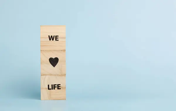 Stock image Wooden cubes with inscriptions We Love Life on a blue background close-up