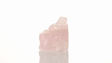 Pembe kuvars mineral taşı yakın plan beyaz arkaplanda daire çiziyor.