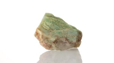 Amazonite mineral taşı yakın plan beyaz bir zeminde daireler çiziyor.