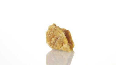 Kalsit sarı mineral taşı yakın plan beyaz zeminde daireler çiziyor.