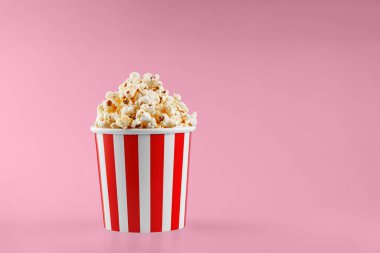 Kırmızı arka planda klasik kırmızı çizgili patlamış mısır karton bardak.