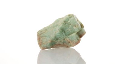 Amazonite mineral taşı yakın plan beyaz bir zeminde daireler çiziyor.