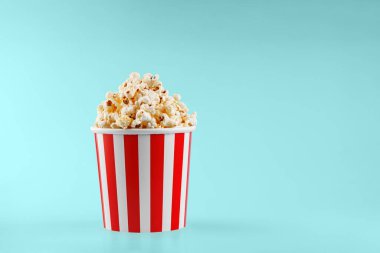 Mavi arka planda klasik kırmızı çizgili patlamış mısır karton bardak.