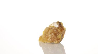 Kalsit sarı mineral taşı yakın plan beyaz zeminde daireler çiziyor.