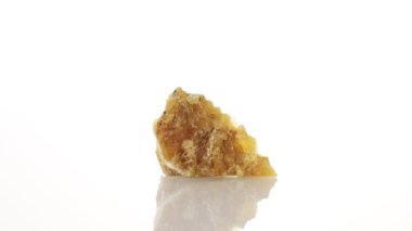 Kalsit sarı mineral taşı yakın plan beyaz zeminde daireler çiziyor.