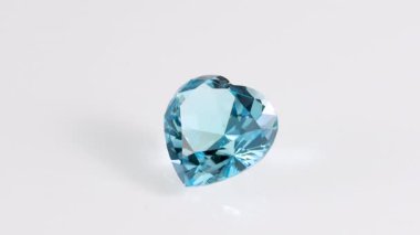 Aquamarine blue facated heart cut stone mineral makro video beyaz izole arka planda bir daire içinde dönüyor yakın çekim