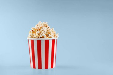 Mavi arka planda klasik kırmızı çizgili patlamış mısır karton bardak.