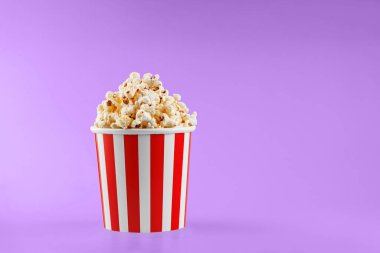 Pembe arka planda klasik kırmızı çizgili patlamış mısır karton bardak.