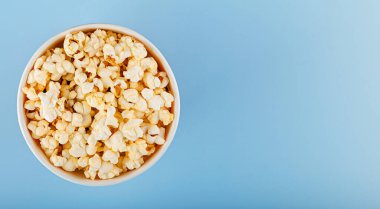 Mavi arka planda klasik kırmızı çizgili patlamış mısır karton bardak.