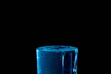 Su damlası düşüyor, makro sıçrama. Doğal ve karanlık bir arkaplanda yakın plan.