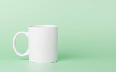 Yeşil arka planda çay ya da kahve içmek için beyaz bardak.