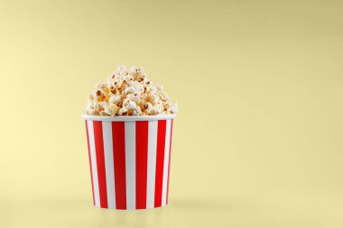 Sarı arka planda klasik kırmızı çizgili patlamış mısır karton bardak.