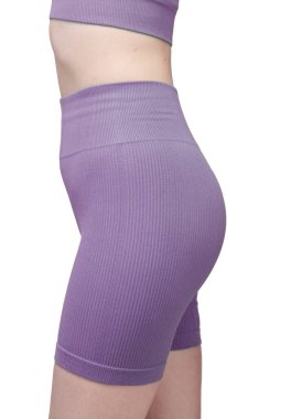 Gri kurdeleli atletik giysili bir kadının poposunun detaylı görüntüsü. Yüksek bel şort onun kıvrımlarını vurguluyor. Kumaşın tırtıklı dokusu açıkça görülüyor. Stüdyo ışıklandırması, beyaz arka plan. Spor kıyafetleri ve fitness reklamları için uygun. 