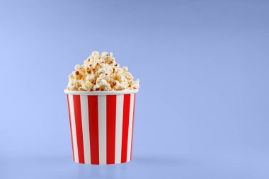 Mavi arka planda klasik kırmızı çizgili patlamış mısır karton bardak.